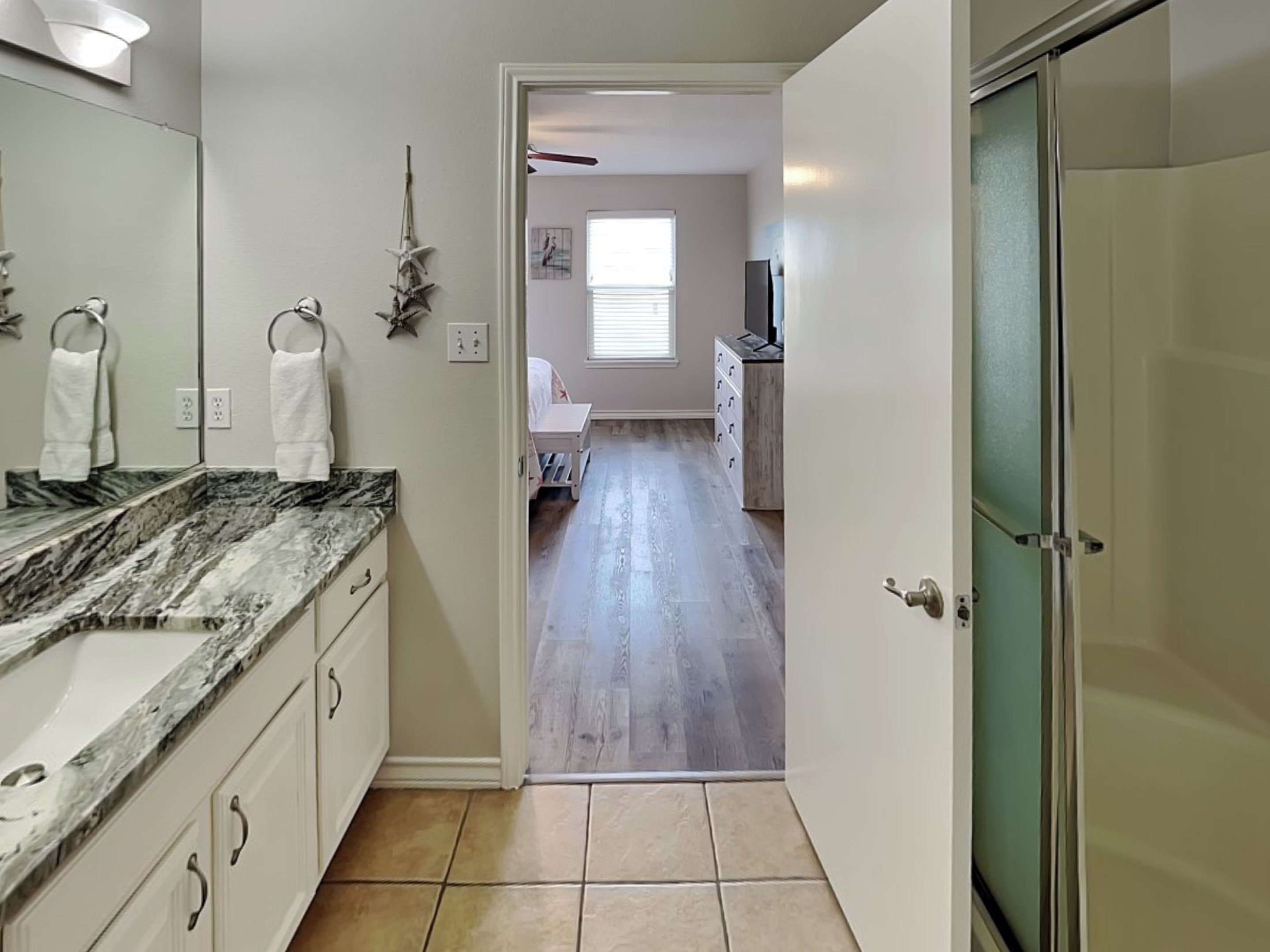 A bathroom with a marble countertop, a mirror, and a towel rack.