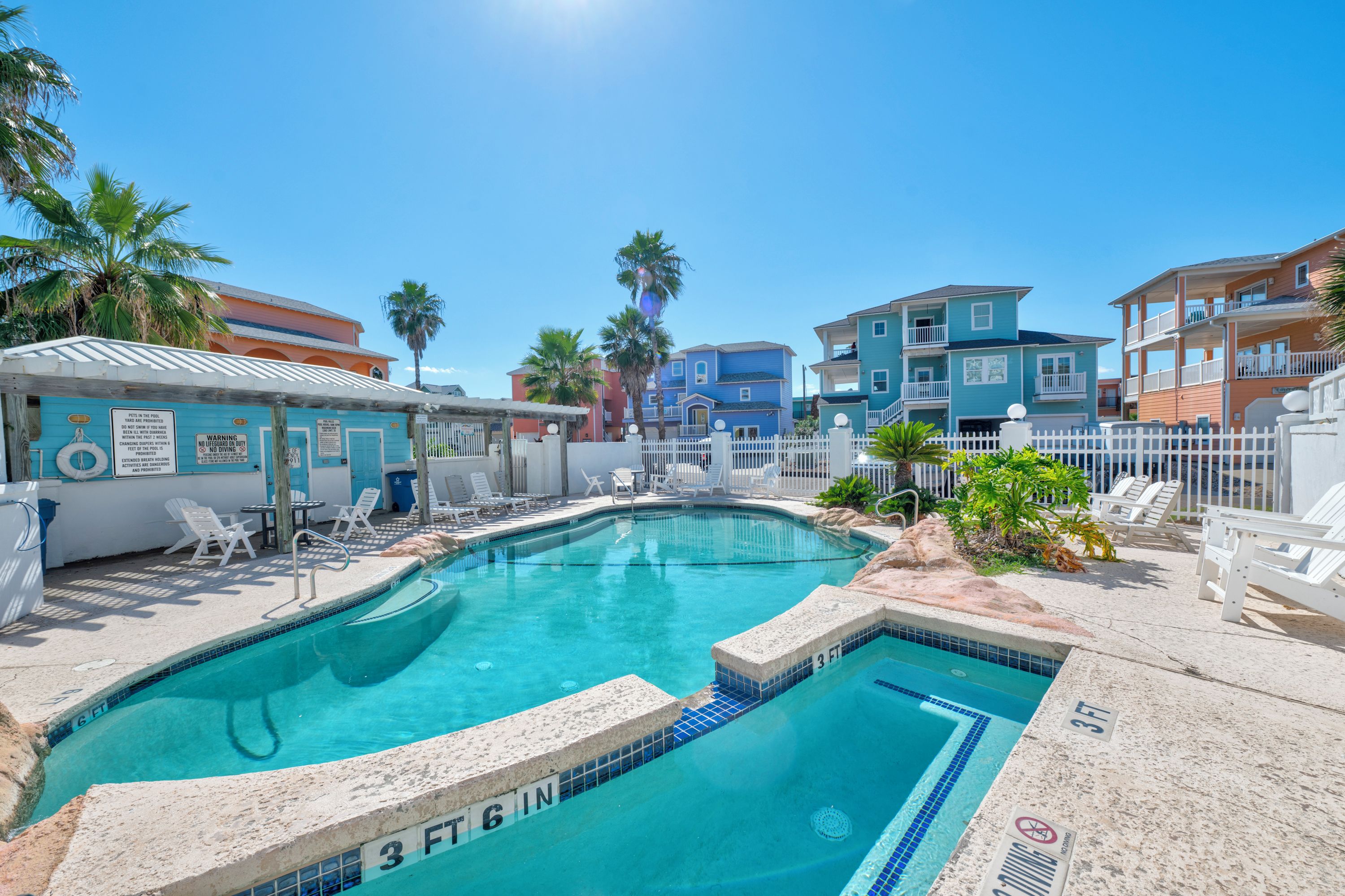 A swimming pool with a 3 FT 6 IN depth marker, surrounded by lounge chairs and a white fence.