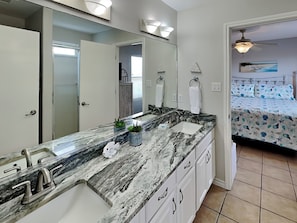 A bathroom with a marble sink, two towel rings, and a ceiling fan.