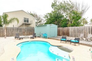A backyard with a swimming pool, wooden deck, and outdoor furniture.