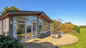 A modern house with a large glass door and a wooden deck. - 10 Horizon View (Liskeard)