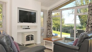 A modern living room with a flat-screen TV, a fireplace, and a large sliding glass door to the outdoors. - 10 Horizon View (Liskeard)