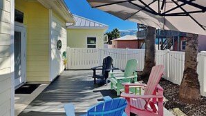 A wooden deck with Adirondack chairs and a white fence. - Coastal Cutie by Silver Sands Vacation Rentals (Port Aransas)