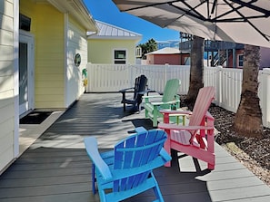 Eine Holzterrasse mit Adirondack-Stühlen und einem weißen Zaun.