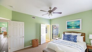 A bedroom with a bed, a ceiling fan, a window with a view, and a door leading to another room. - Casa La Vista by Silver Sands Vacation Rentals (Port Aransas)
