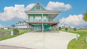 Une maison à deux étages avec un balcon, un garage et un ciel dégagé.