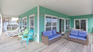 A covered porch with wicker furniture and a green exterior wall. - Casa La Vista by Silver Sands Vacation Rentals (Port Aransas)