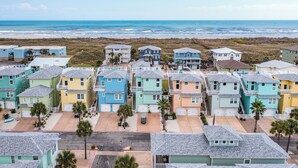 Zona residencial costera con casas coloridas, una playa y un cielo despejado.