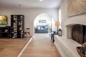 A living room with a fireplace, a sofa, a TV, and a bookshelf. - Scottsdale Oasis | Pickleball, Pool, Spa & Hoops (Scottsdale)