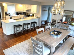 A modern kitchen with a central island, bar stools, a dining table with benches, and a chandelier. - Saratoga Springs Arts District Home (Saratoga Springs)