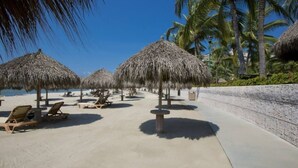 A beachside resort with thatched umbrellas, sun loungers, and a clear view of the ocean.