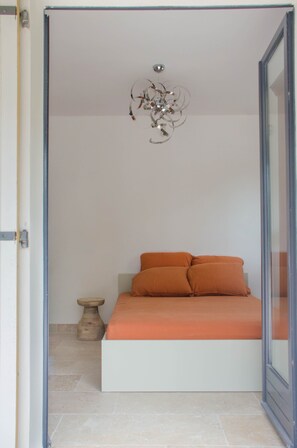A bedroom with a bed, a decorative ceiling light, and a small wooden stool. - Villa des jacinthes (Tarascon)