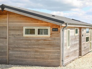 Eine Holzhütte mit zwei Fenstern und einem Schild mit der Aufschrift 'HV12'.