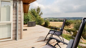 Eine Terrasse mit zwei Stühlen und einem Tisch, mit Blick auf eine ländliche Gegend.