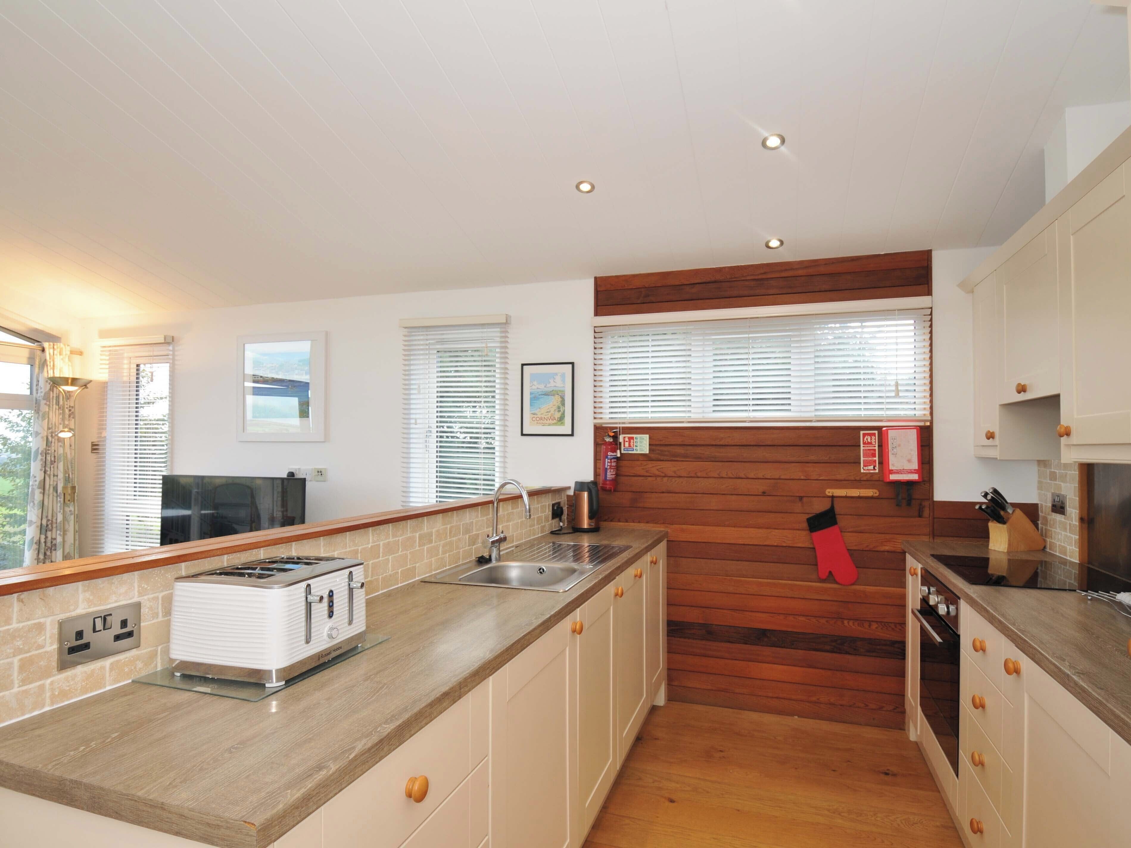 A modern kitchen with a central island, wooden accents, and white cabinetry.