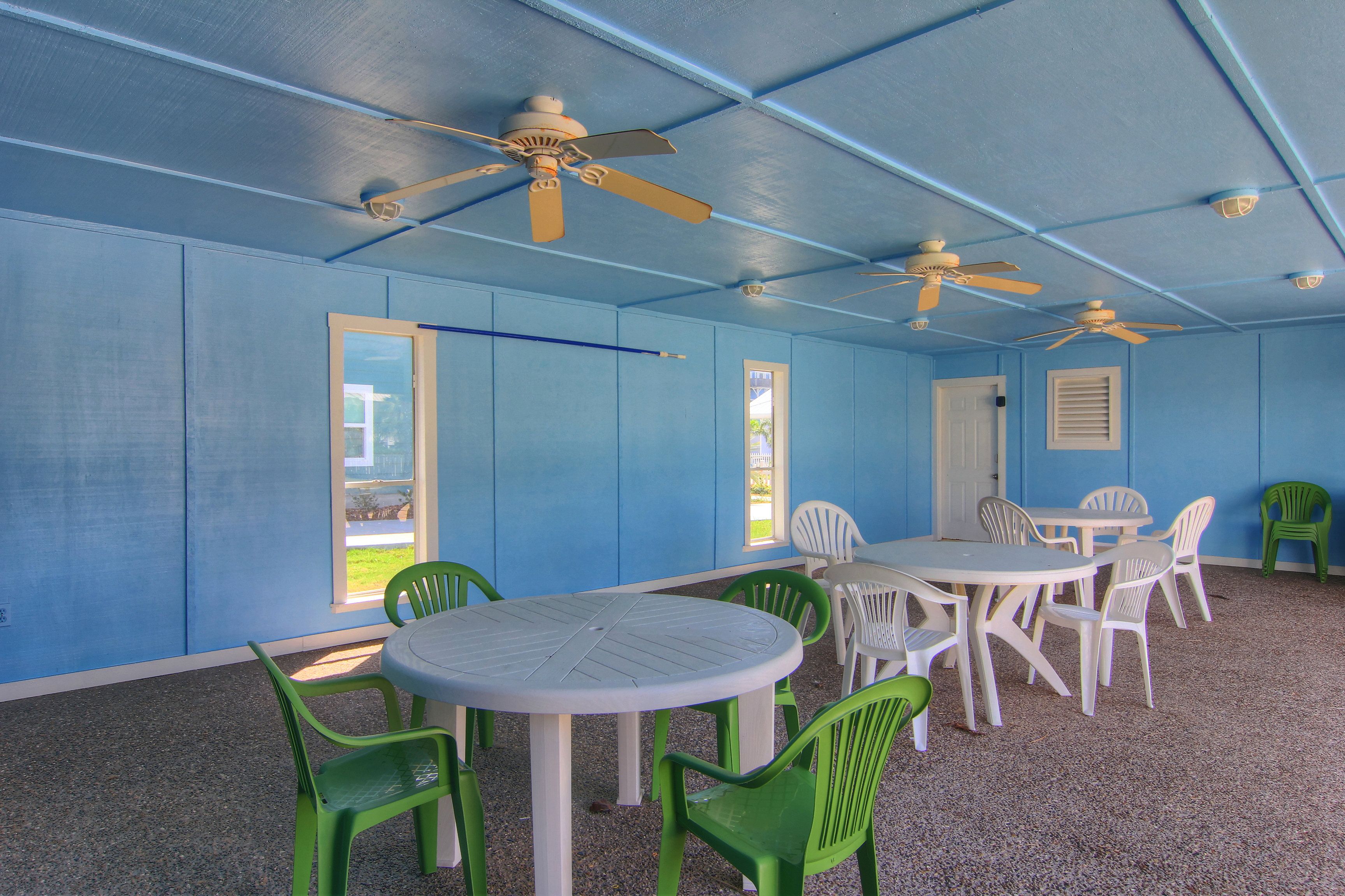 Ein Zimmer mit blauen Wänden, weißen Deckenventilatoren und einem runden Tisch mit Stühlen.