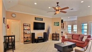 A living room with a red sofa, a coffee table, a TV, and a ceiling fan.
