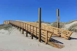 Een houten looppad dat over zandgrond loopt, met een bord waarop de maximumsnelheid staat en een waarschuwing voor een militair gebied.