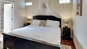 A bedroom with a bed, bedside tables, a window, and a door.