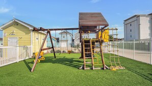 A playground with swings, a climbing structure, and a fenced area.