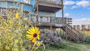 A multi-story building with a wooden deck and stairs leading to an upper level. - Crandall's Cottage by Silver Sands Vacation Rentals (Port Aransas)