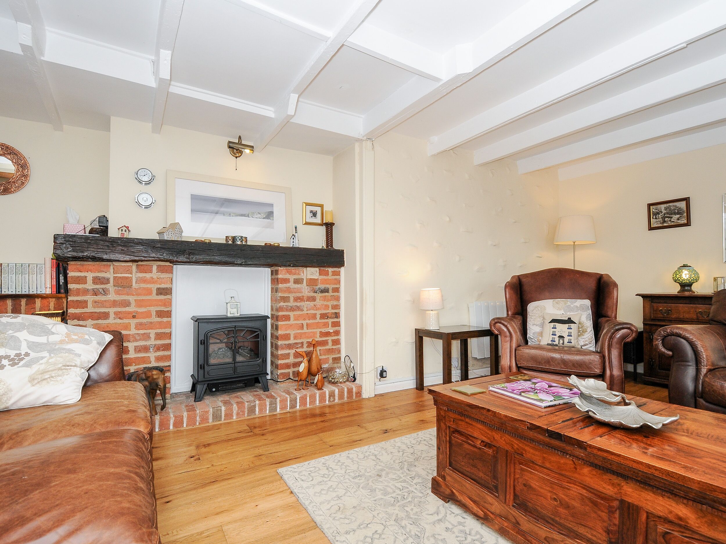 A cozy living room with a brick fireplace, leather furniture, and a wooden coffee table.