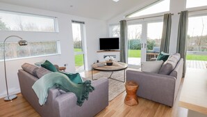 A modern living room with two sofas, a TV, and a wooden coffee table. - 14 Horizon View (Liskeard)