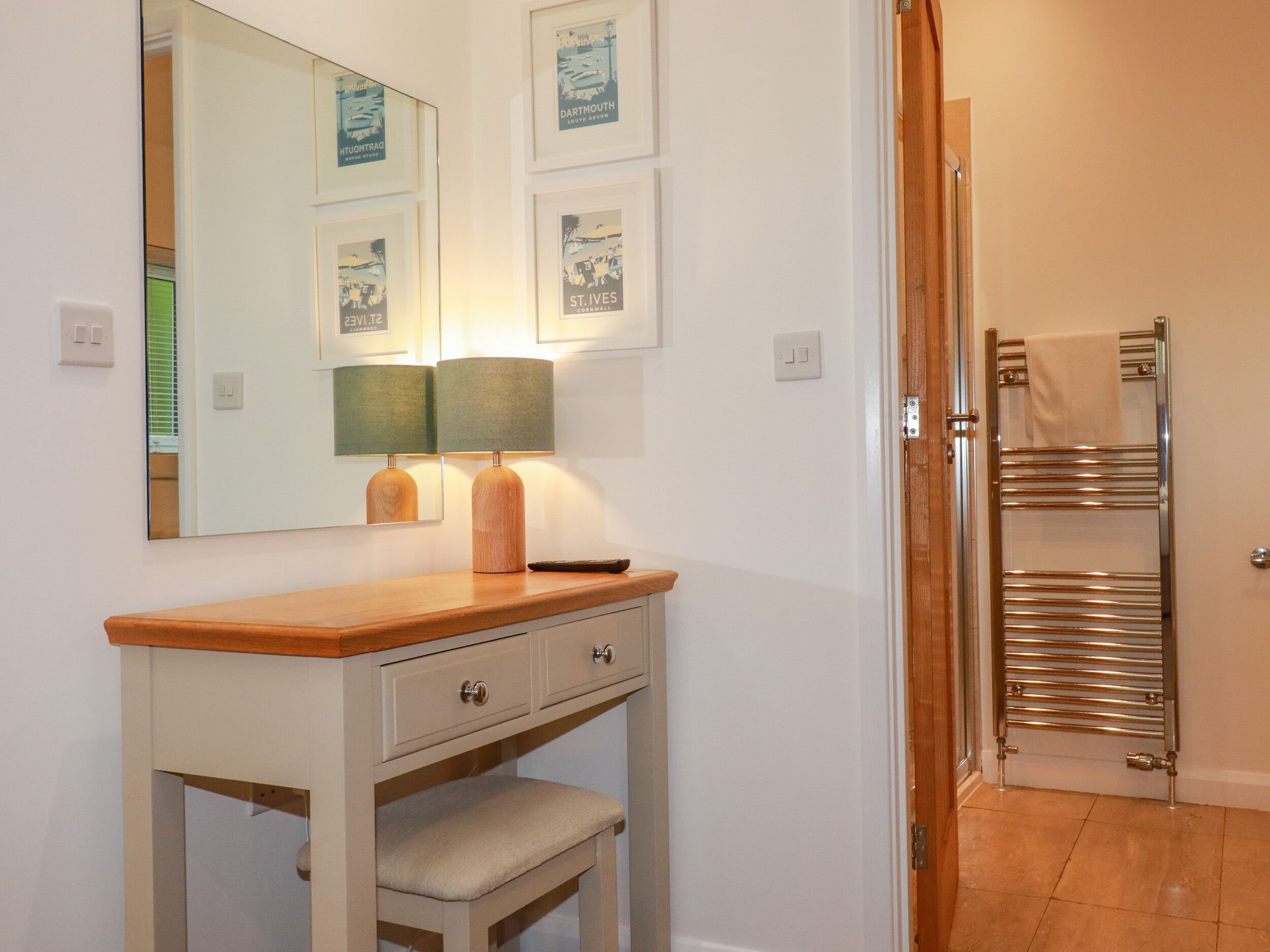 A bathroom with a wooden vanity, a mirror, framed pictures on the wall, and a towel rack.