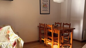 Ein Zimmer mit Esstisch, Stühlen, einer Couch und einer Hängelampe.