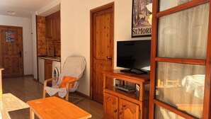 Ein Wohnzimmer mit Holzmöbeln, einem Fernseher und einem Poster an der Wand.