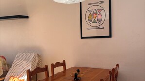 Ein Essbereich mit Holztisch, Stühlen, einer Pendelleuchte und einem gerahmten Bild an der Wand.