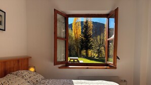 Ein Schlafzimmer mit Bett, einem Fenster mit Blick auf einen Park und einem Holzkopfseitenverkleidung.