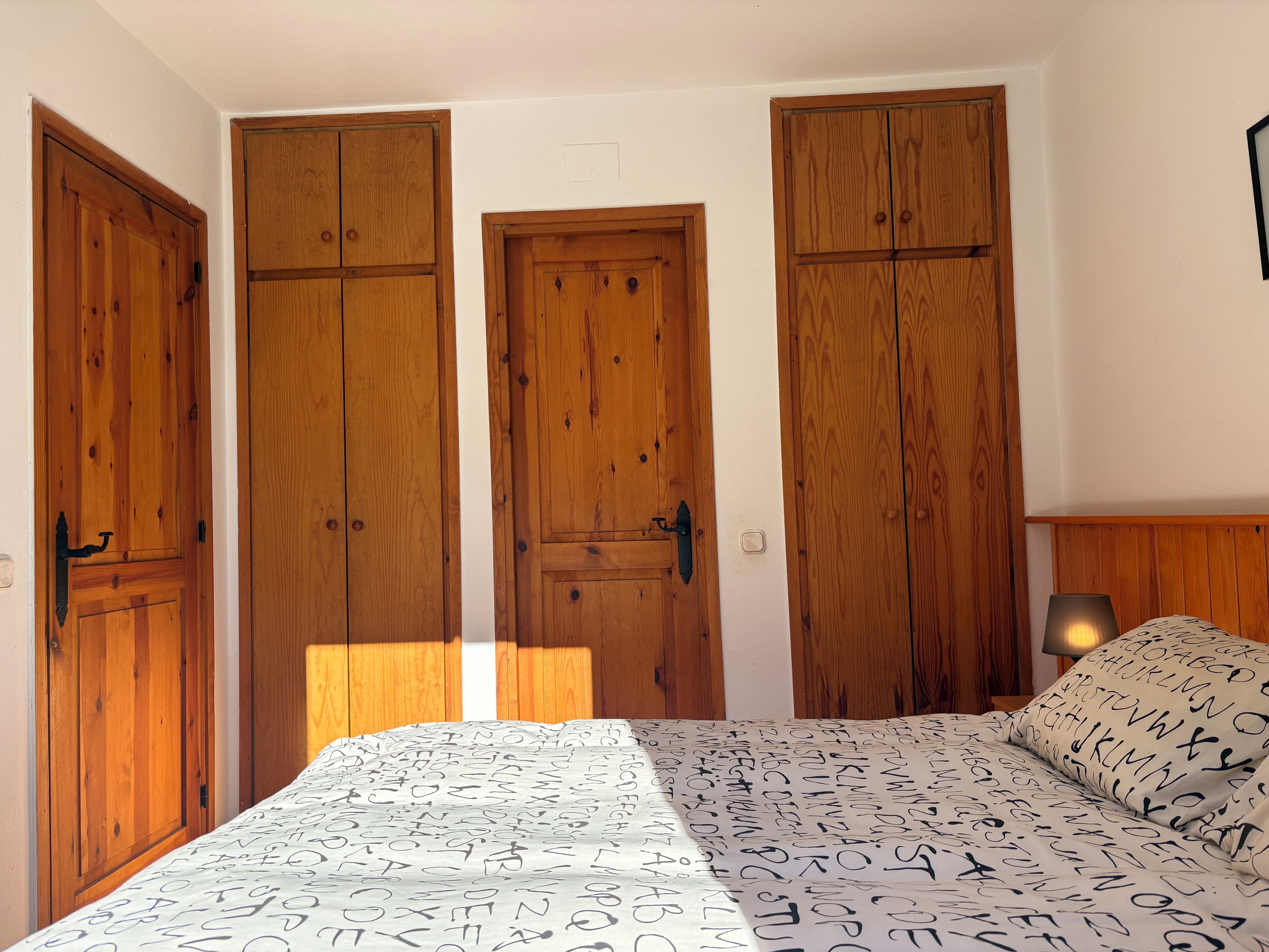 Una camera da letto con un letto, un armadio in legno e un comodino.