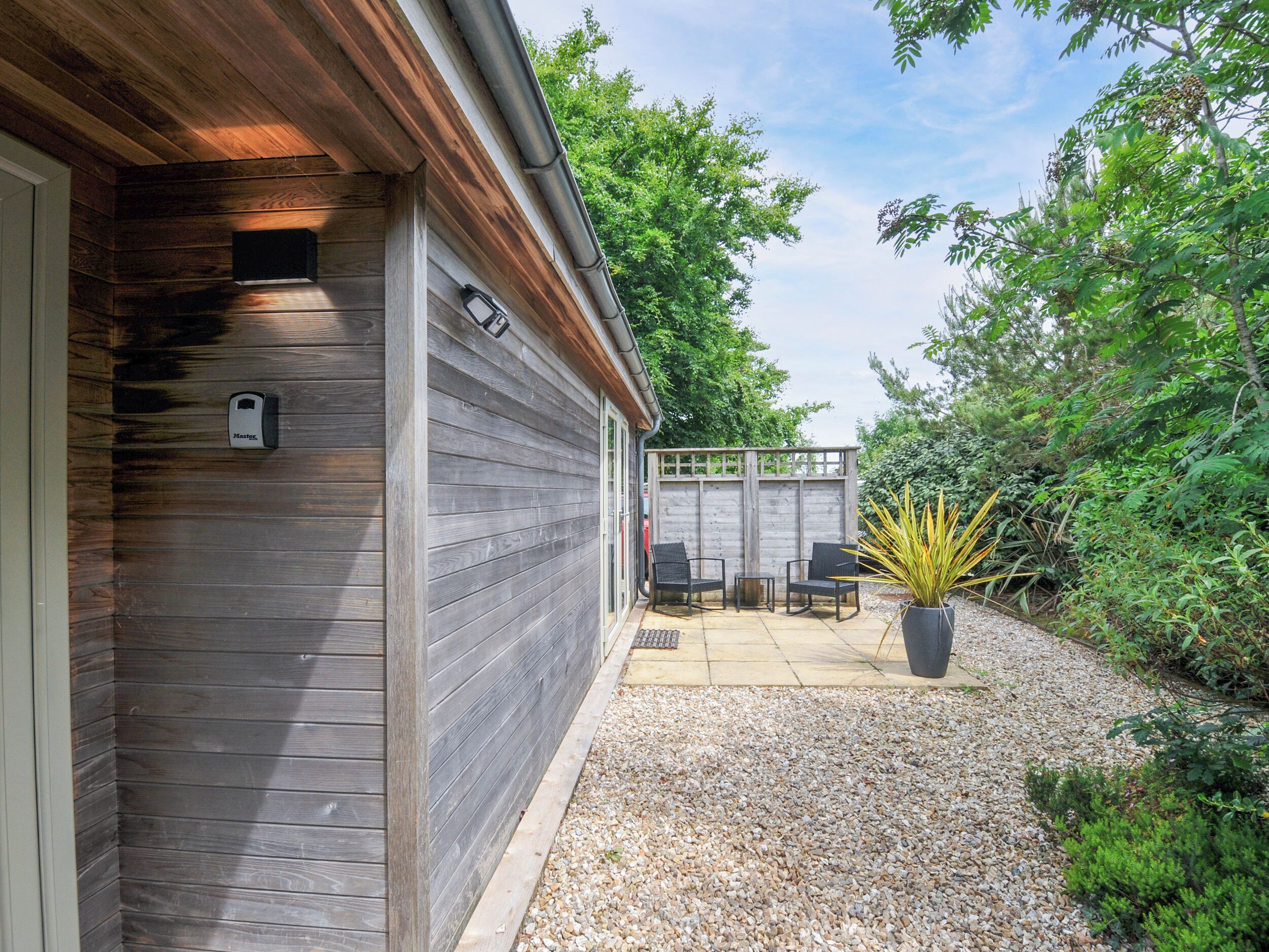 A wooden house with a patio area, outdoor seating, and a potted plant.