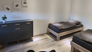 A bedroom with a bed, a dresser, and three framed pictures on the wall.