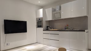 A modern kitchen with built-in appliances, a flat-screen TV, and wooden stools.