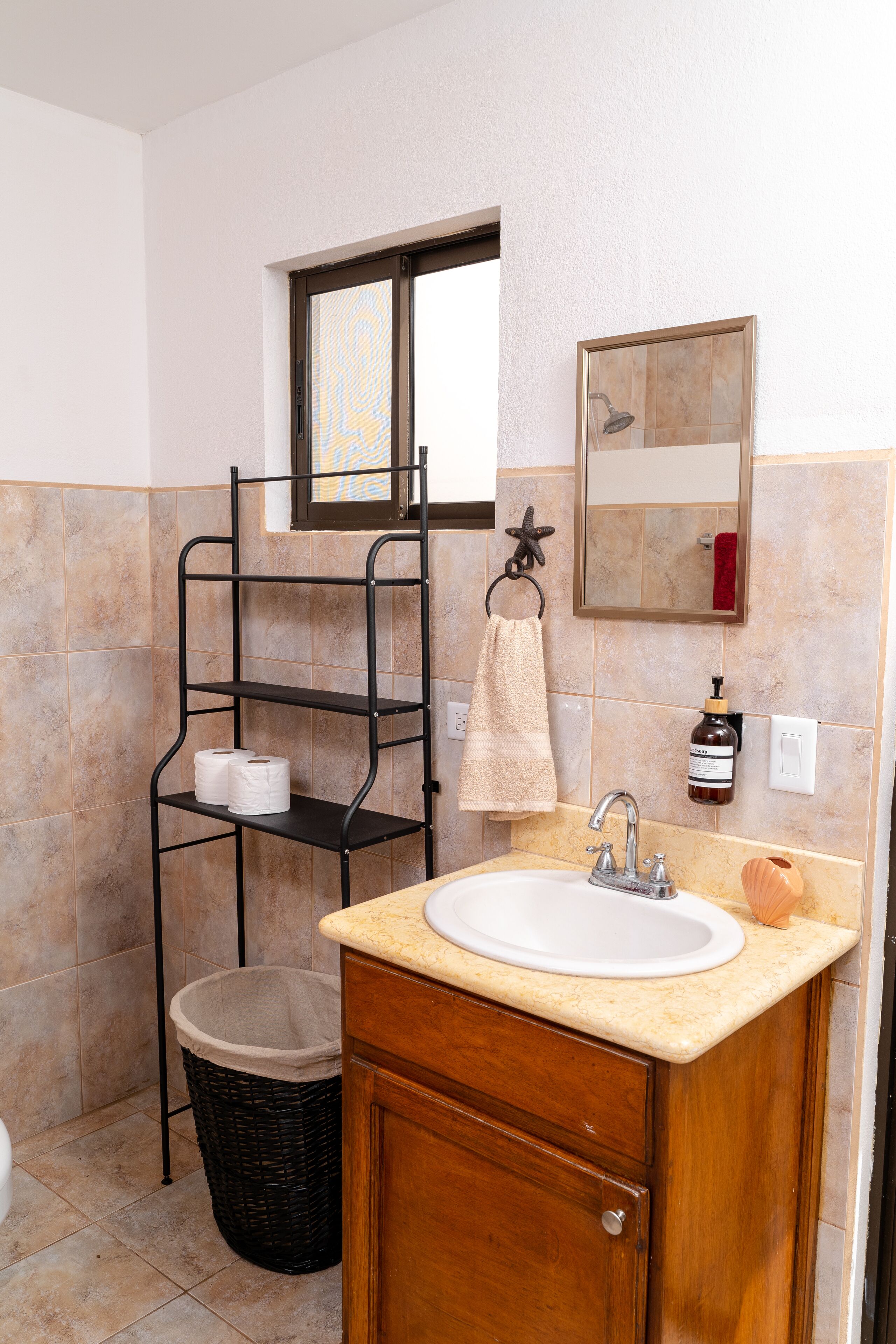 Une salle de bain équipée d’un lavabo, d’un miroir et d’étagères où sont rangées les serviettes.