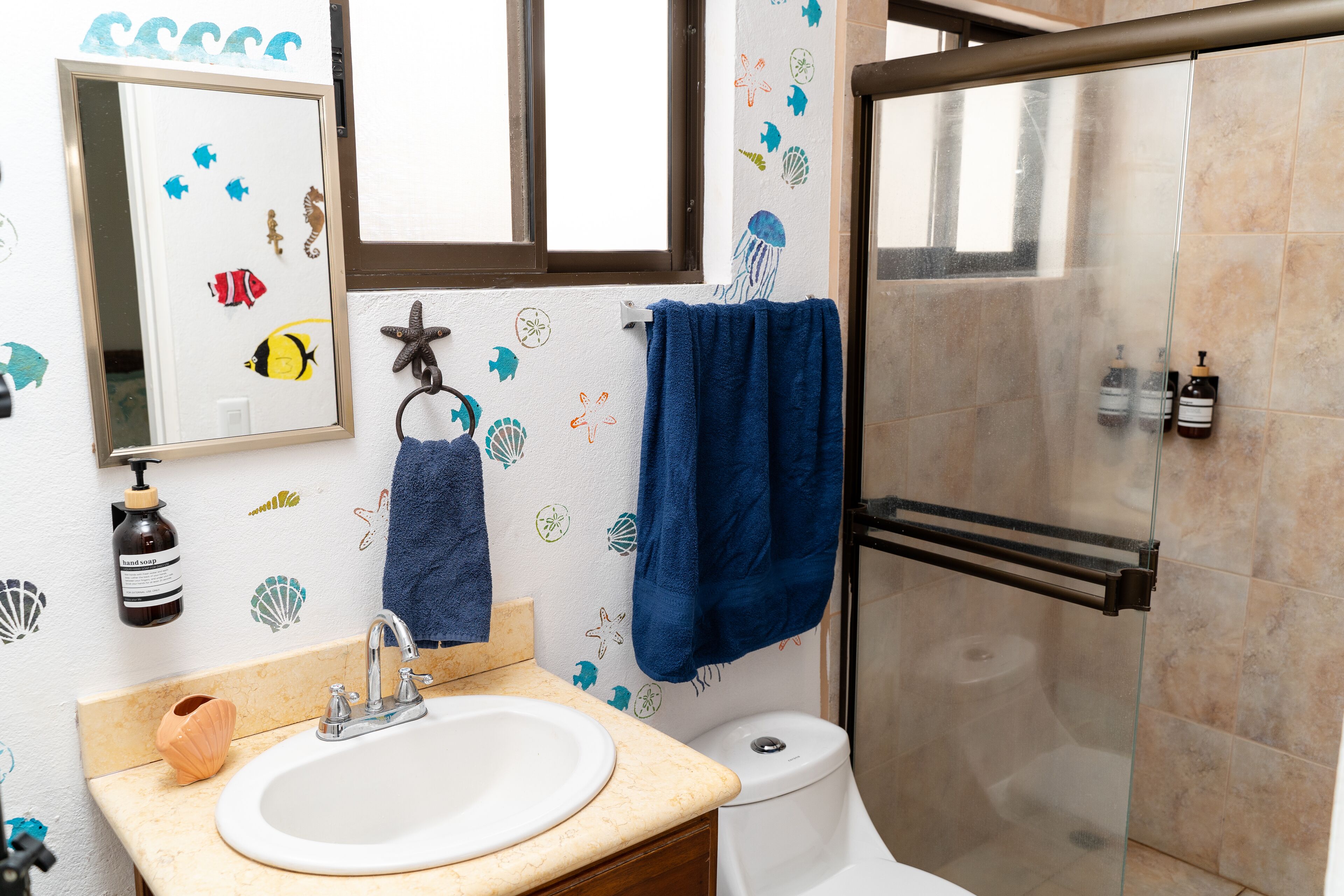 A bathroom with a sink, mirror, and shower.
