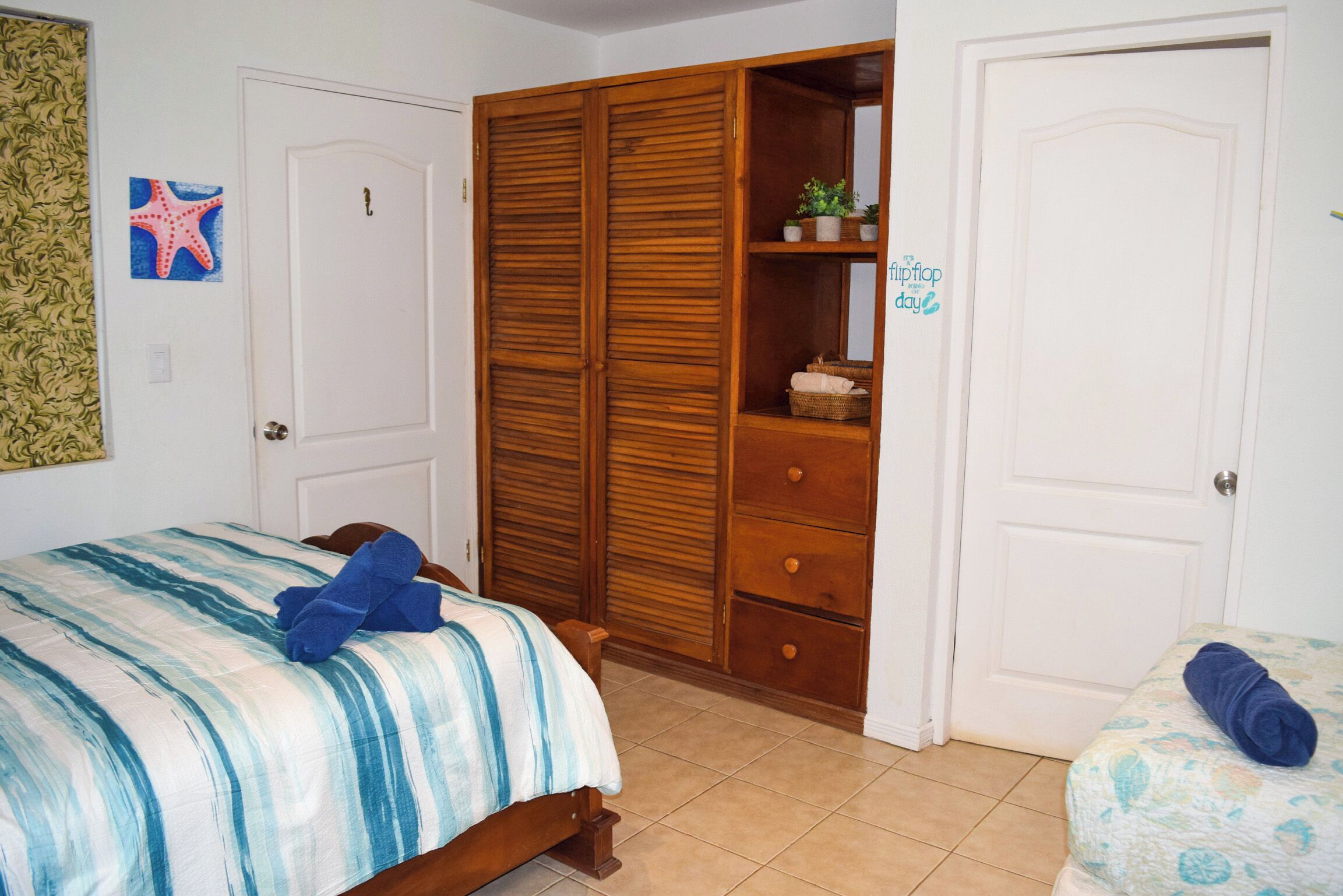Een slaapkamer met een bed, een houten garderobe en een klein tafeltje met een plant.