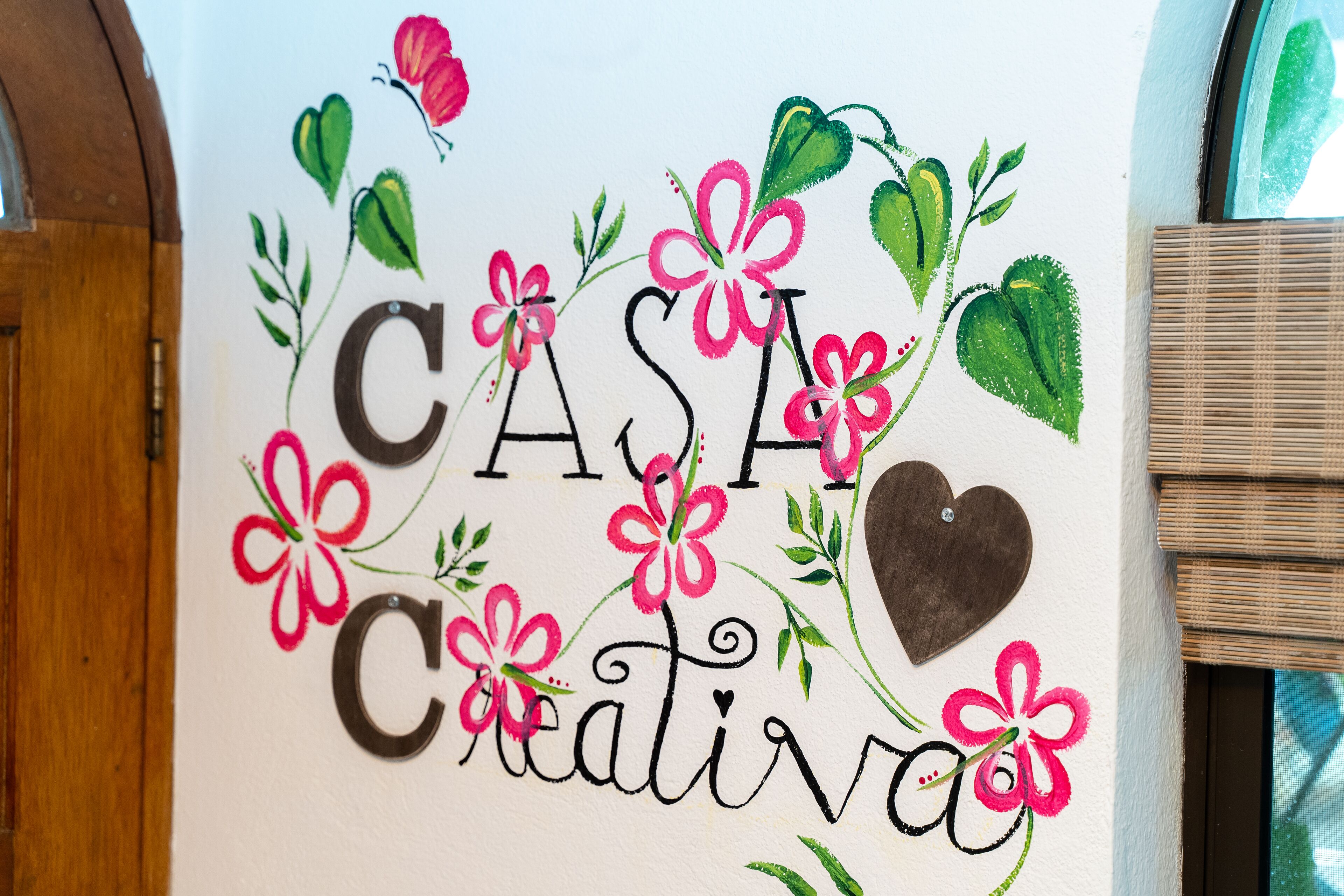 Een muur met de tekst "CASA Creativa" omringd door bloemmotieven.