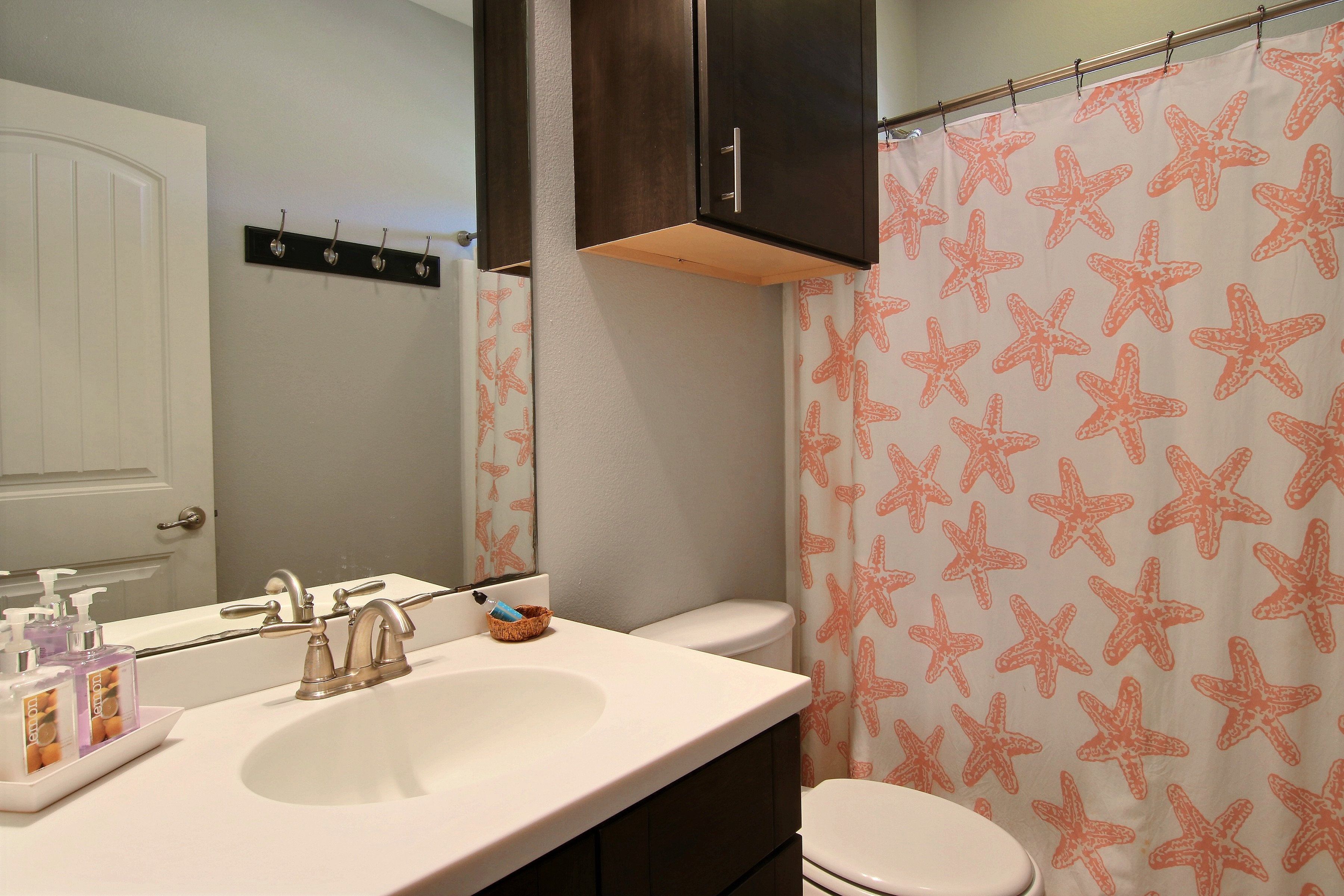 A bathroom with a white sink, a mirror, a cabinet above the sink, and a toilet.