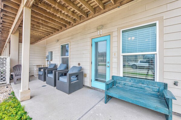 Relax in this inviting outdoor seating area with a bench, wicker chairs, and a small table.