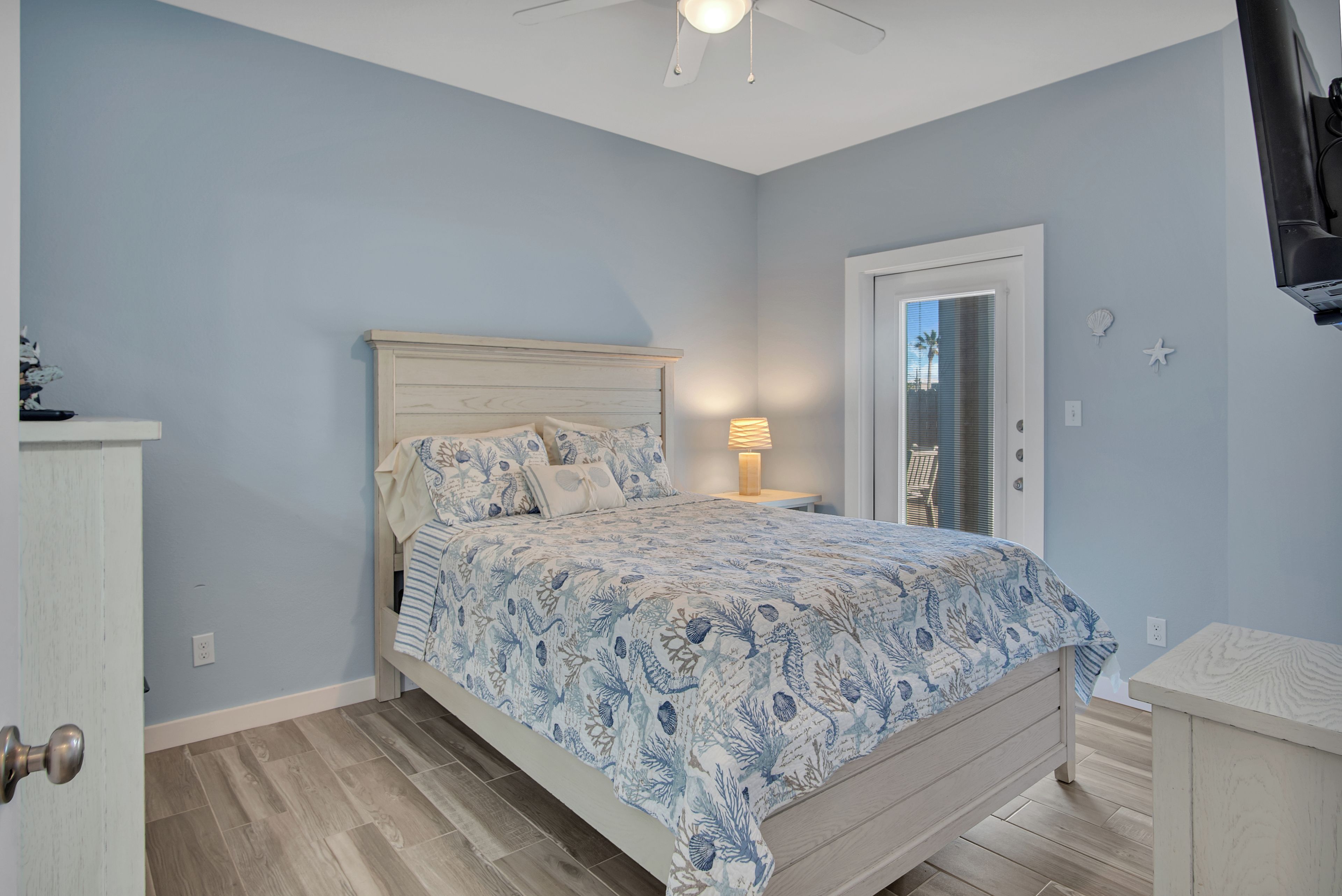 A bedroom with a bed, a nightstand, a lamp, and a door.