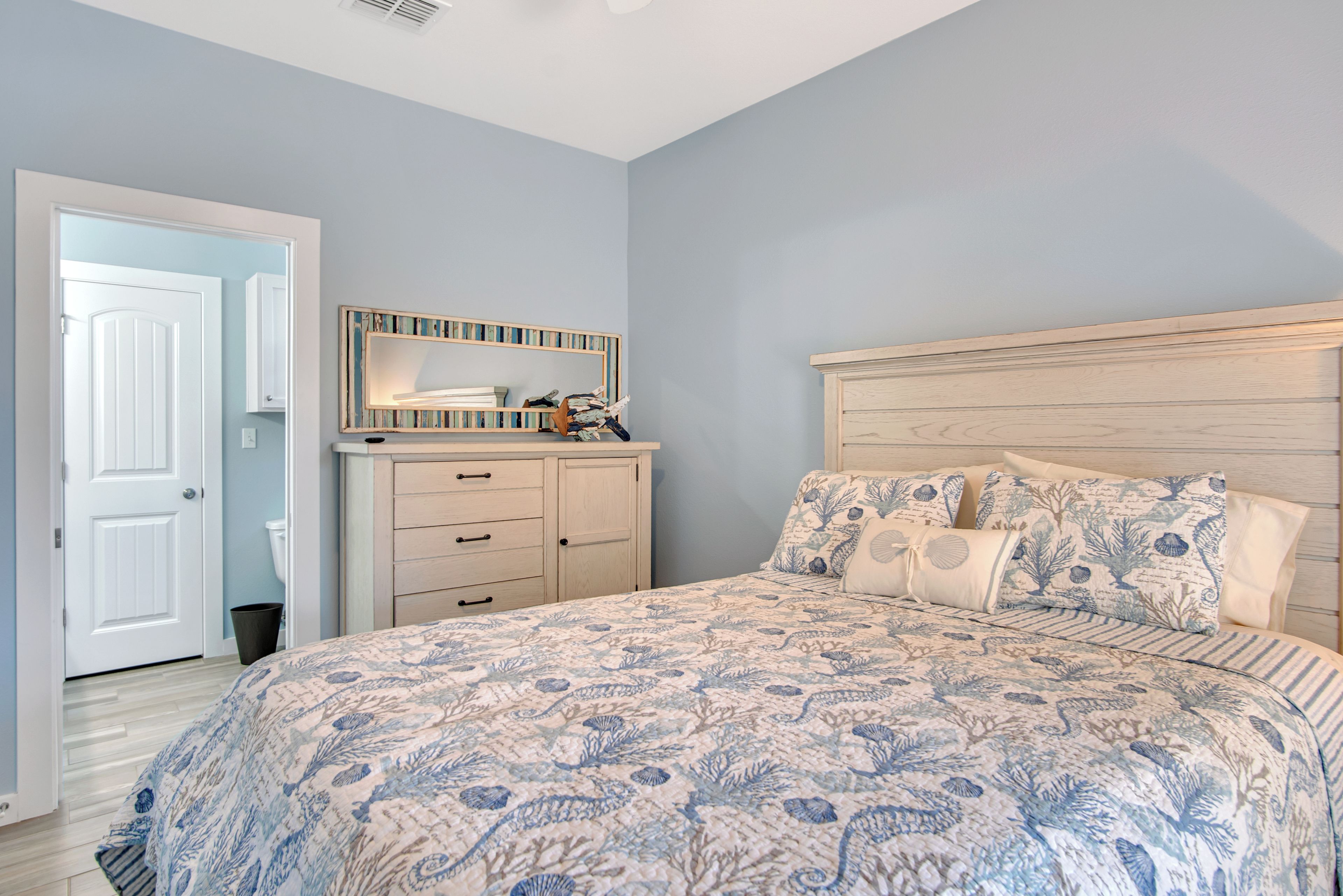 A bedroom with a bed, dresser, and a door.