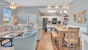 A modern kitchen with white cabinets, a wooden dining table, and a ceiling fan. - Fin And Tonic by Silver Sands Vacation Rentals (Port Aransas)