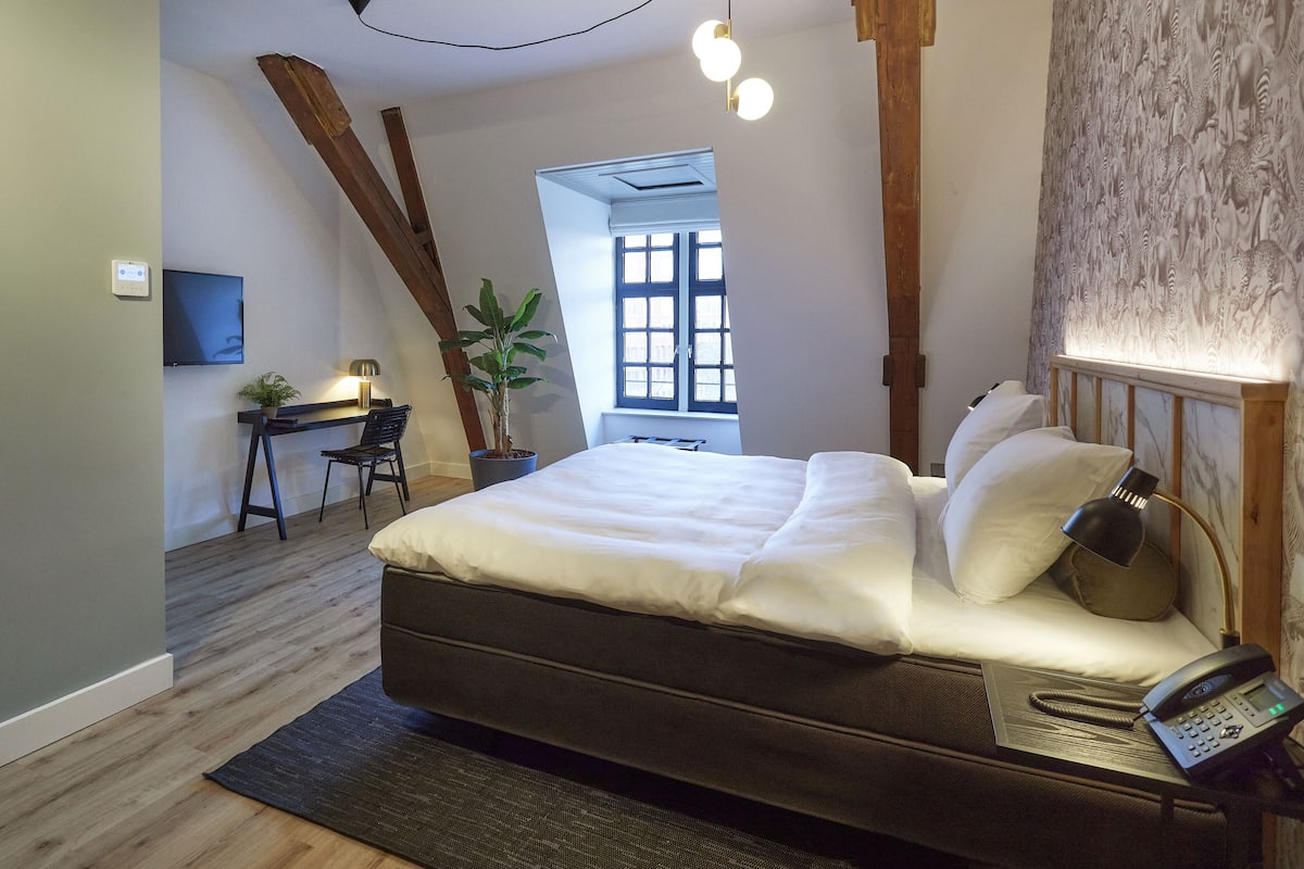 A modern bedroom with a bed, bedside lamp, and a phone on the nightstand.