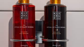 Twee flessen Ritual of Happy Buddha shampoo en douchegel op een witte betegelde muur.