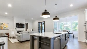 A modern kitchen with a central island, pendant lighting, and a large window providing natural light.