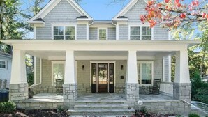 A two-story house with a front porch, stone columns, and a symmetrical facade.
