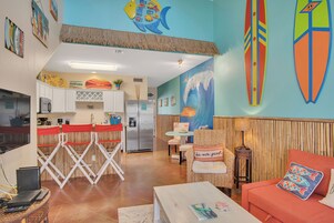Una habitación con cocina, comedor y asientos decorados con adornos de tablas de surf.